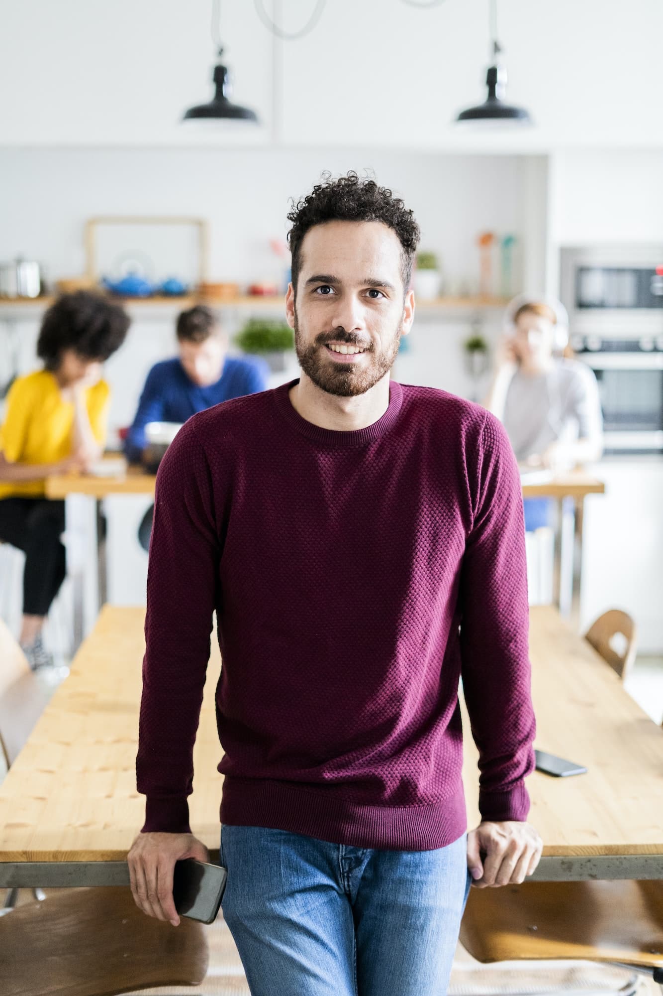 Portrait of smiling man at dining table at home with friends in background